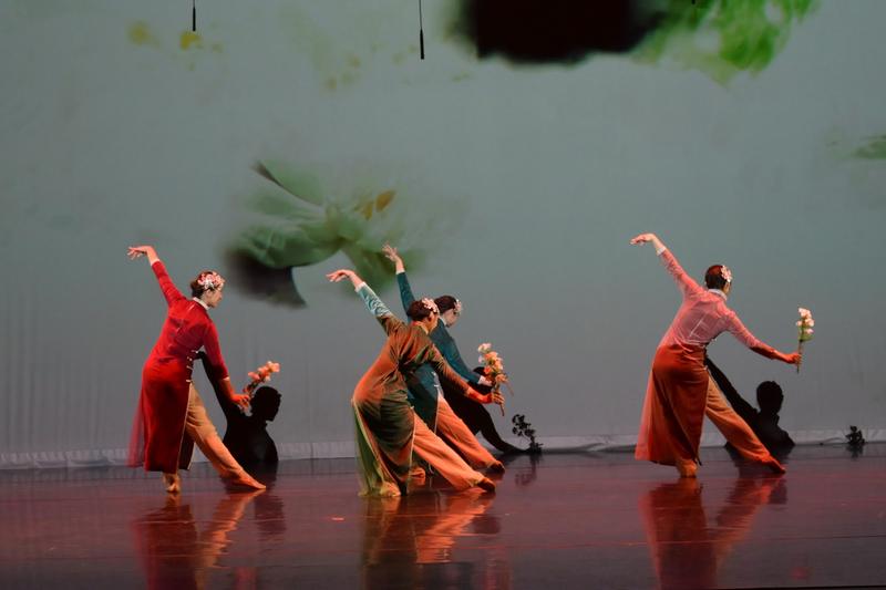 Dancers in qipao holding flowers against an ink-wash projection