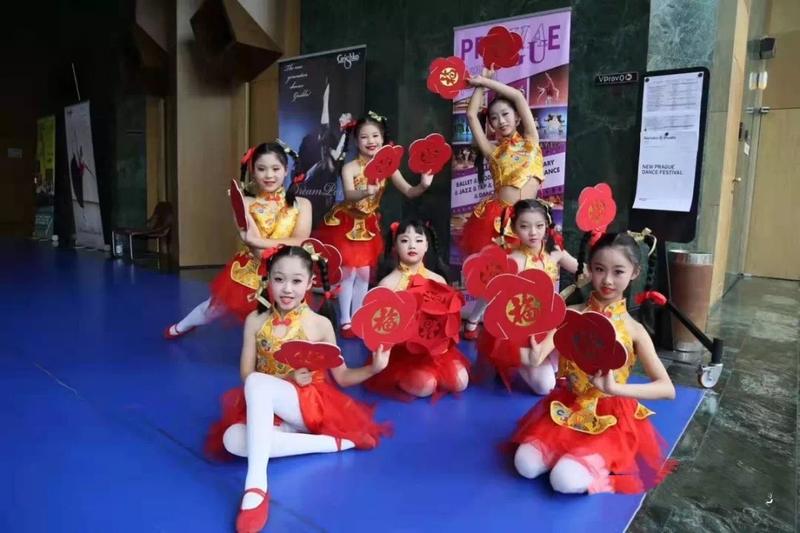 Young dancers in red costumes with fan props backstage at the New Prague Dance Festival