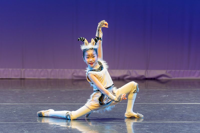 The same character dancer smiling in a deep lunge, one arm raised overhead